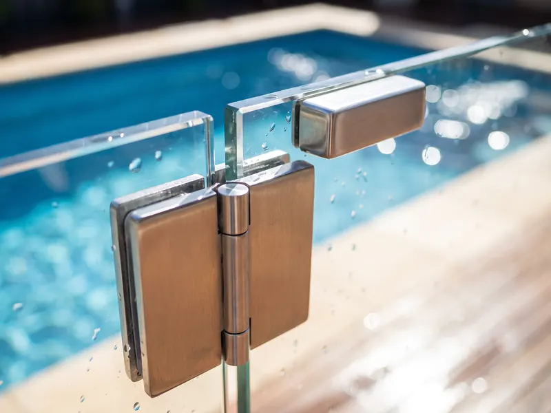 Glass pool fence gate with a self-closing hinge and safety latch